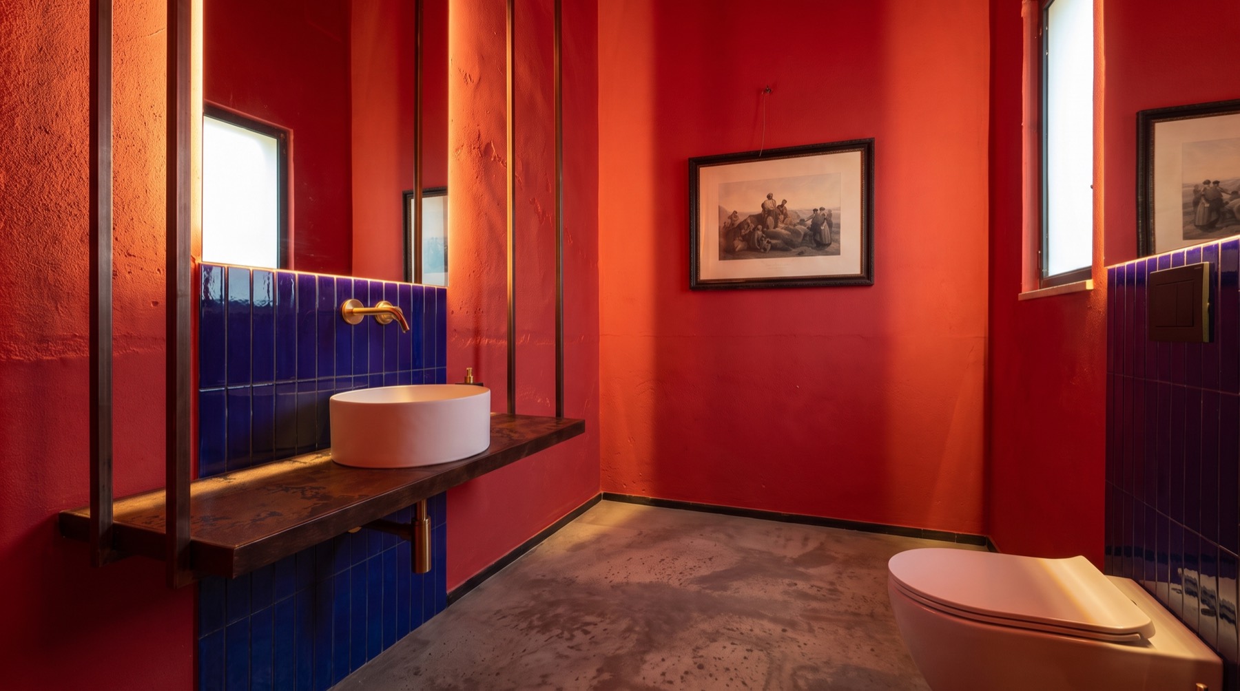 Vista orizzontale del bagno rosso con specchio e stampe alle pareti